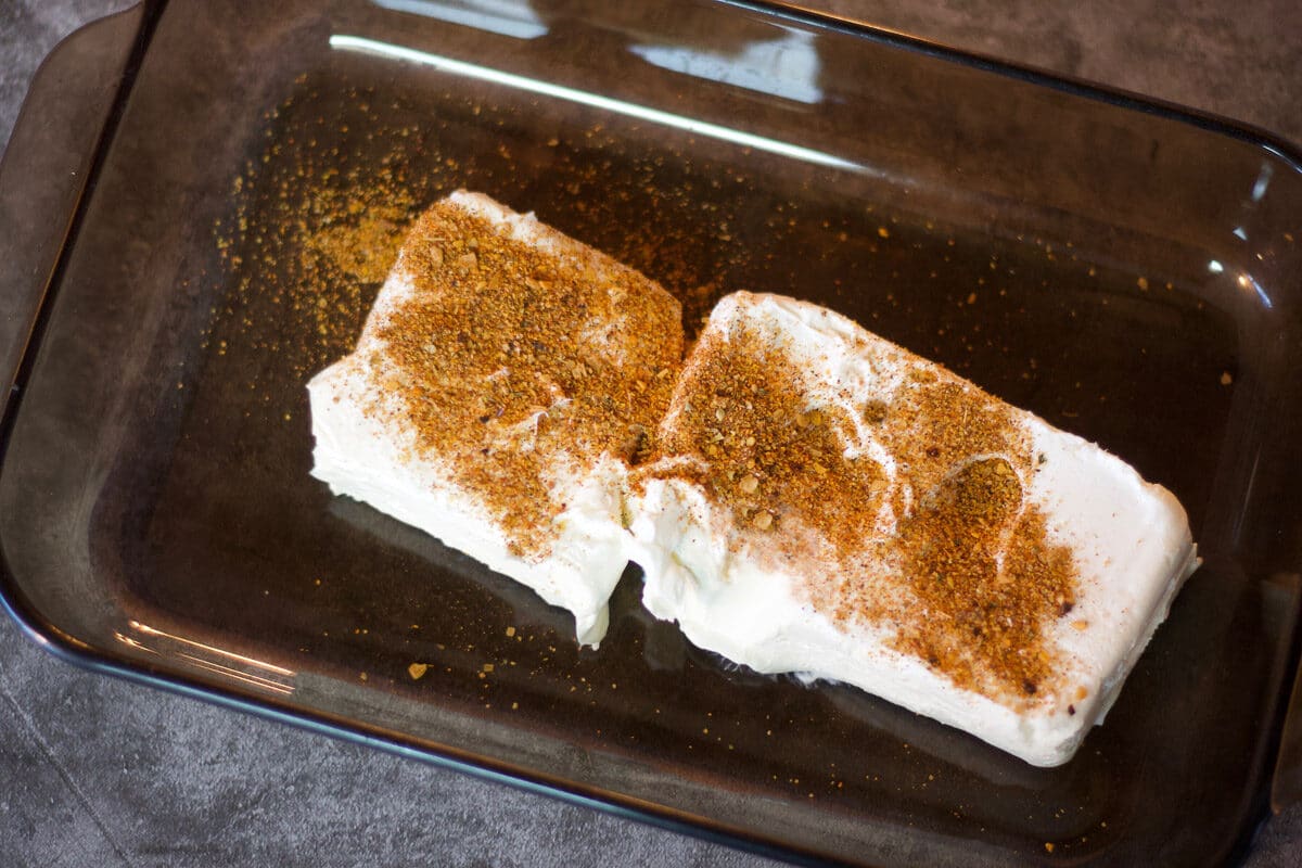 cream cheese covered with taco seasoning in a baking dish