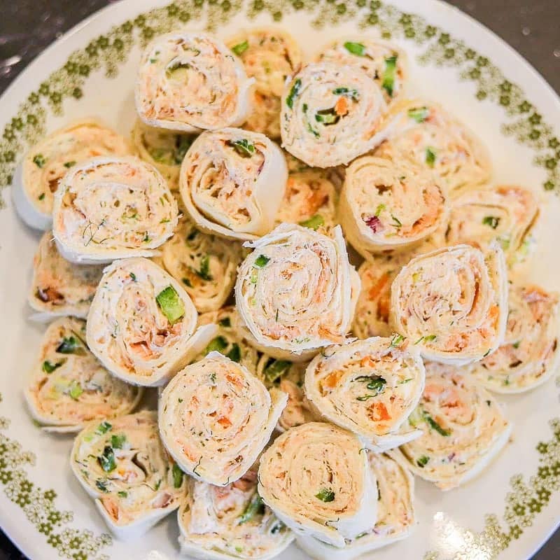New Years eve appetizers: salmon pinwheels on a white plate.