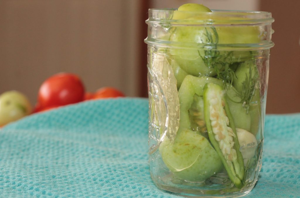 green tomatoes in a mason jar over a blue towel