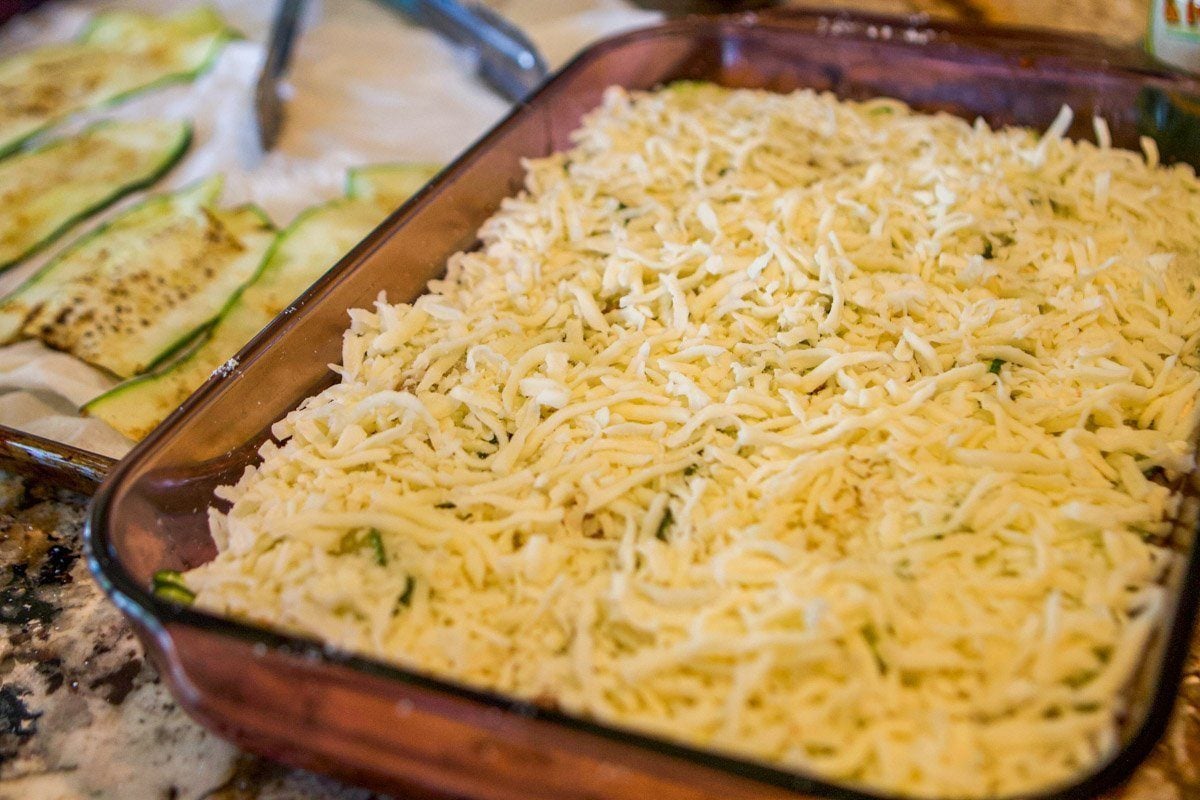 cheesy lasagna layered in a pan with zucchini on the side