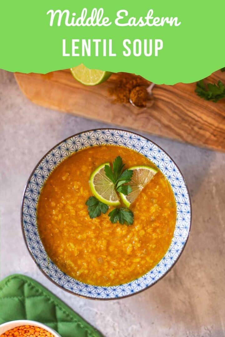 red lentil soup in bowl with lime slices and cilantro