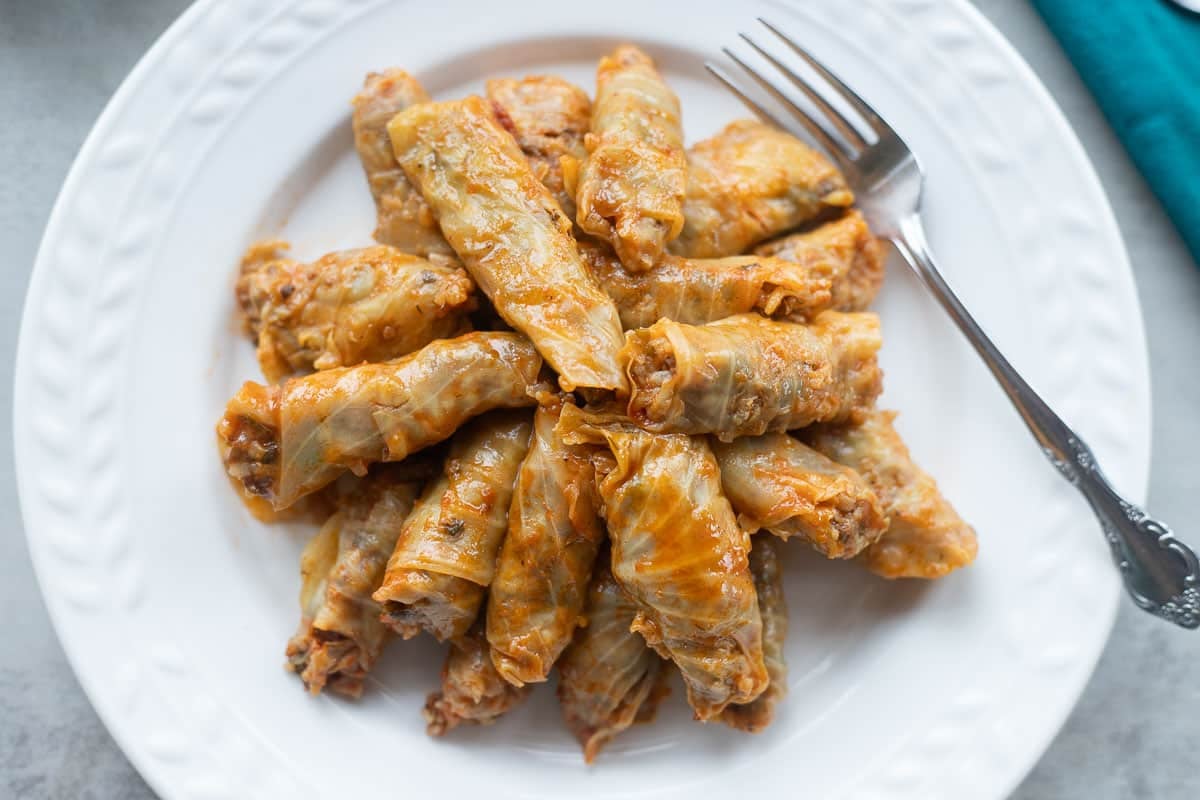 cabbage dolma on a white plate with a fork.