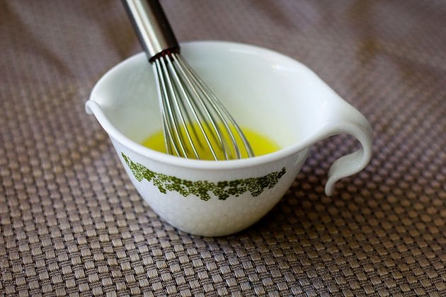 salad dressing in a small cup with a mini whisk