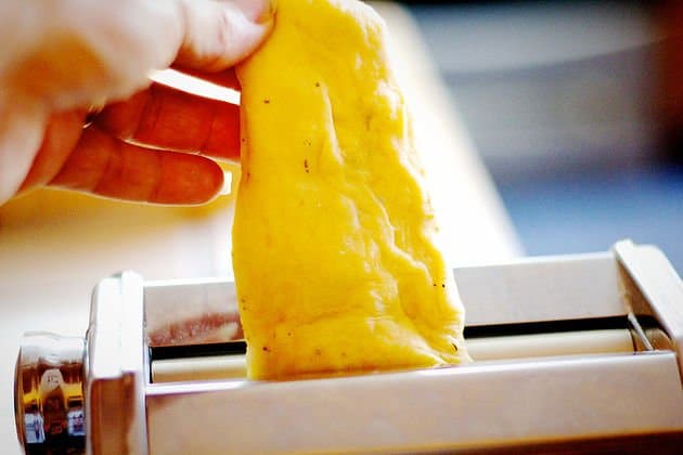 homemade pasta being fed through pasta machine