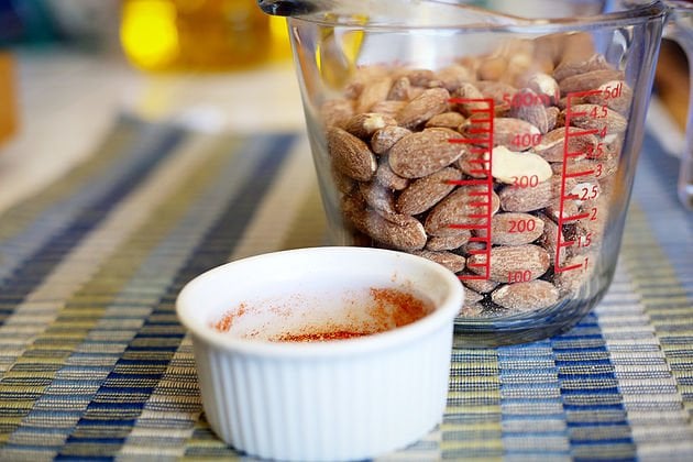 almonds in a measuring cup with a white bowl in front of it