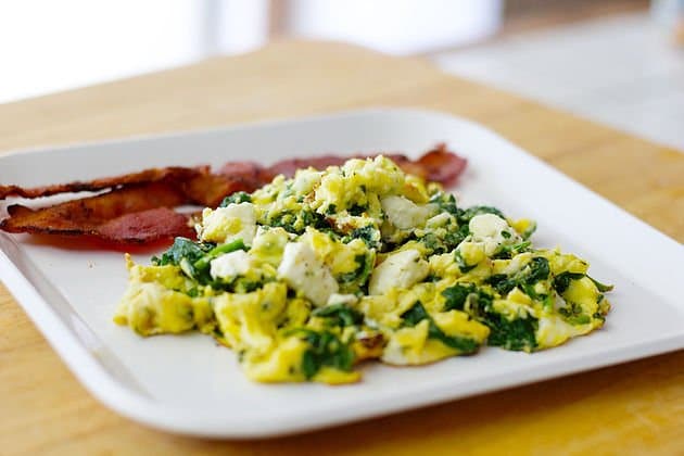 Spinach and Eggs with feta and bacon on a white plate