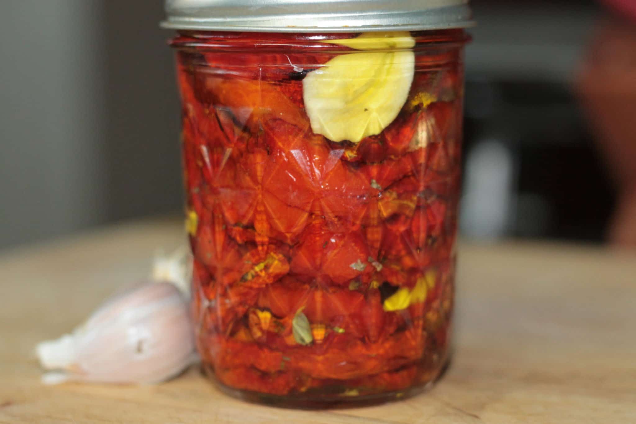 sun-dried tomatoes in a jar with garlic next to it
