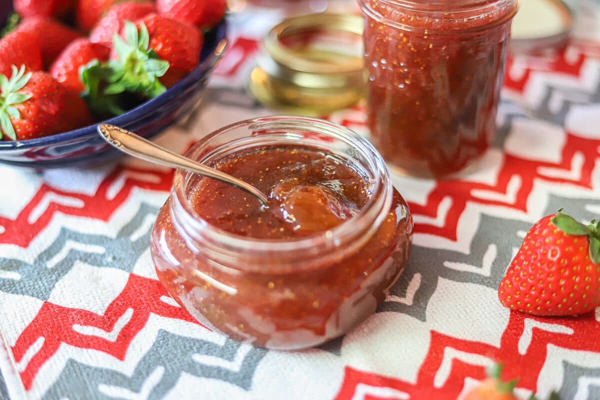 strawberry fig jam in a jar on a red and gray dishtowel