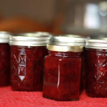 jars of plum preserves on a red dish towel