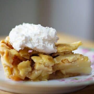Apple pie slice on a plate with whipped cream