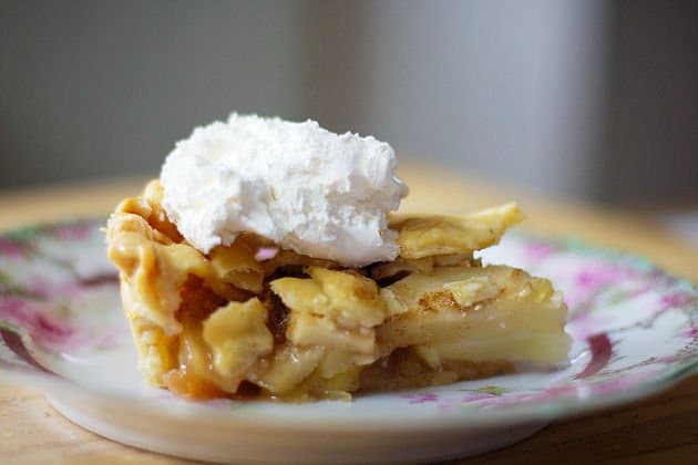 Apple pie slice on a plate with whipped cream
