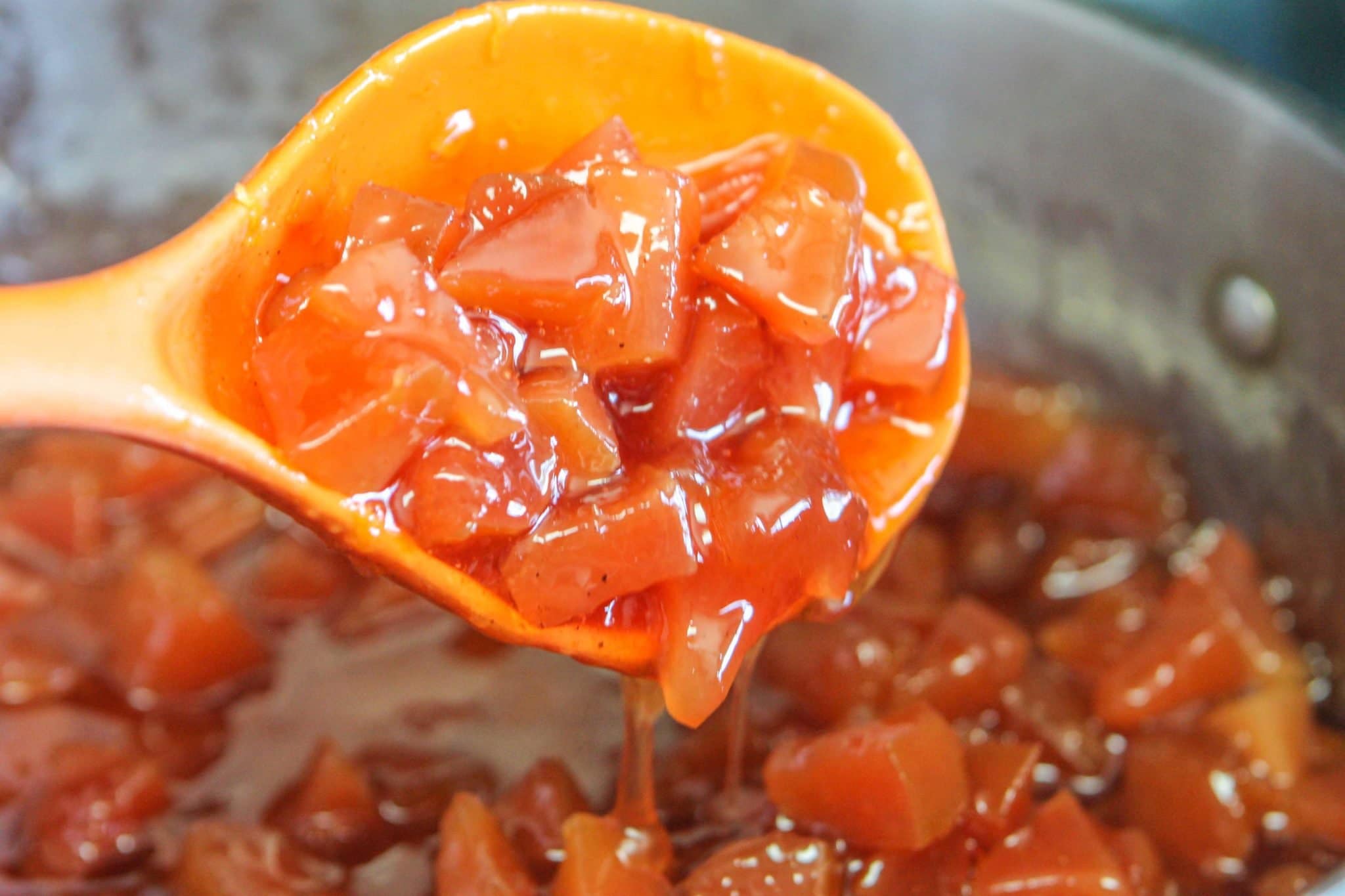 quince jam being scooped by an orange plastic spoon