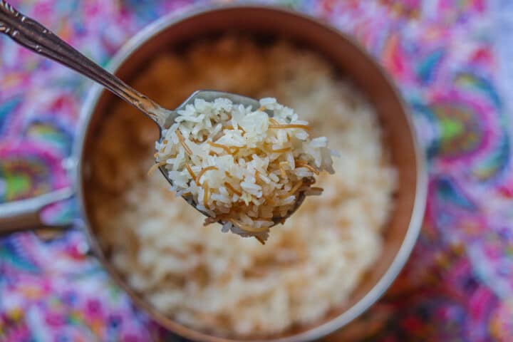 a spoonful of vermicelli rice over a pot of rice