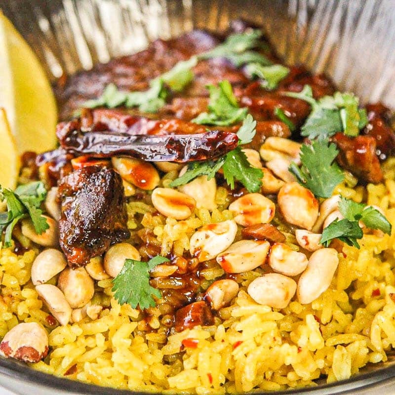 creamy coconut rice with peanuts, pork, lime wedges.