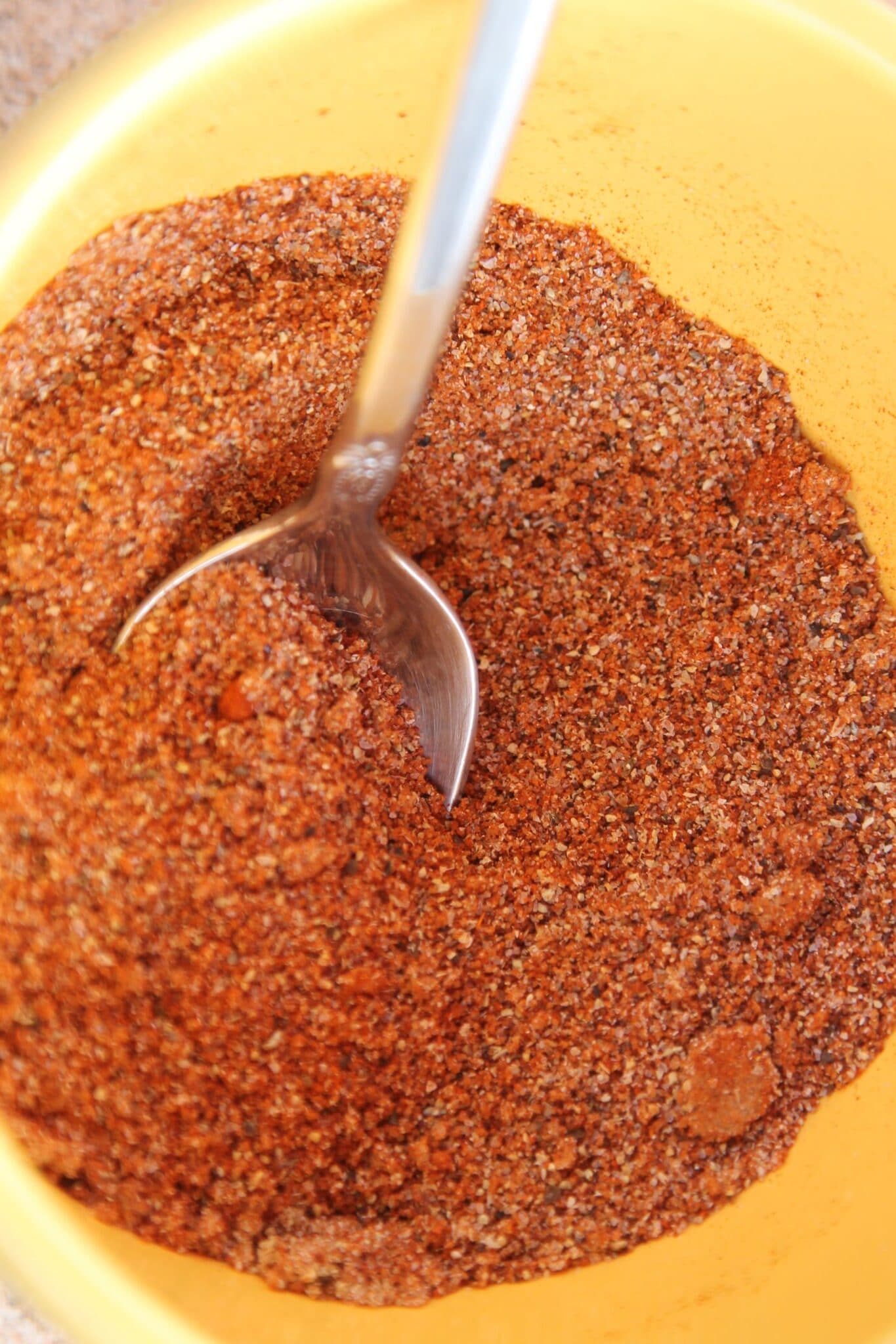 dry rub seasoning in a yellow bowl with a silver spoon