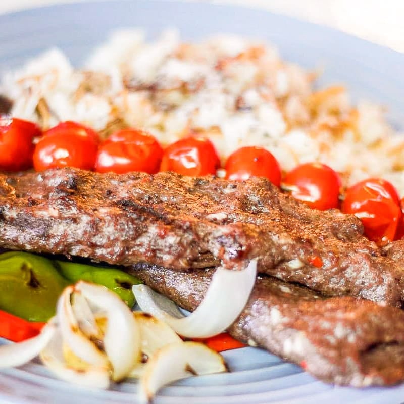 goat kebabs over a bed or rice.