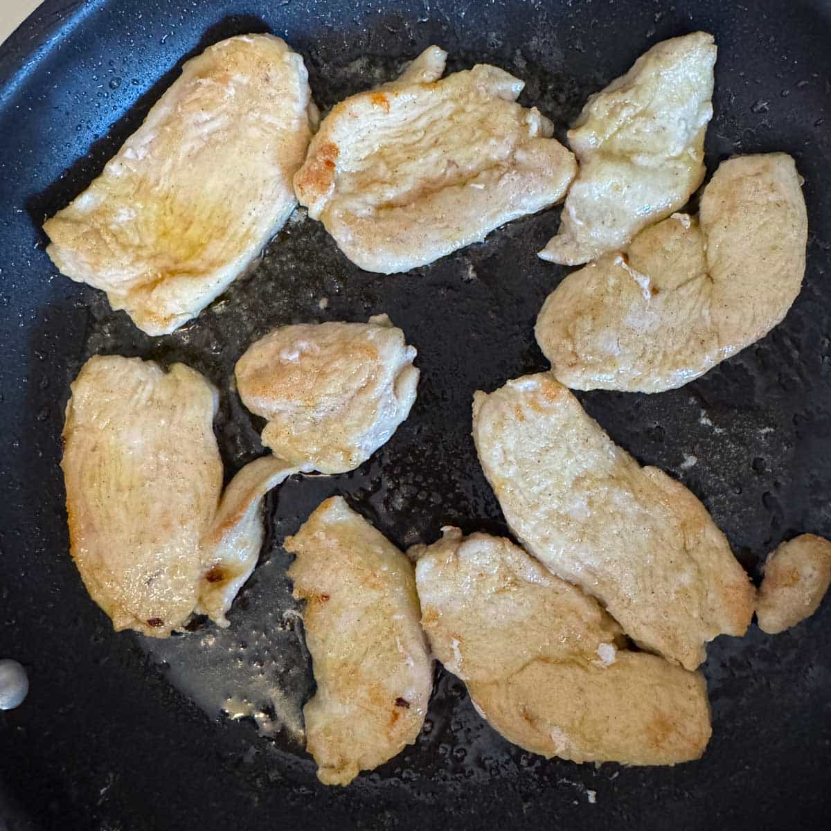 chicken cutlets being fried in a pan