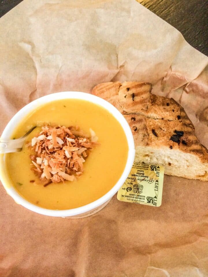 pumkin soup with toasted coconut and bread on the side