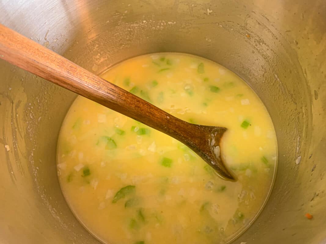 soup being stirred with a wooden spoon
