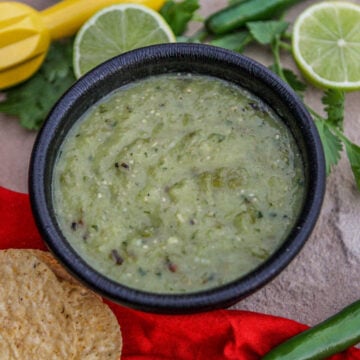 salsa verde with limes and chips around it