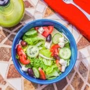 salad in a blue bowl with a red napkin on a marbled table