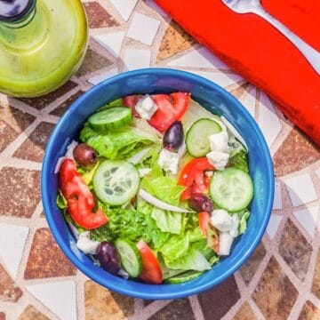 salad in a blue bowl with a red napkin on a marbled table