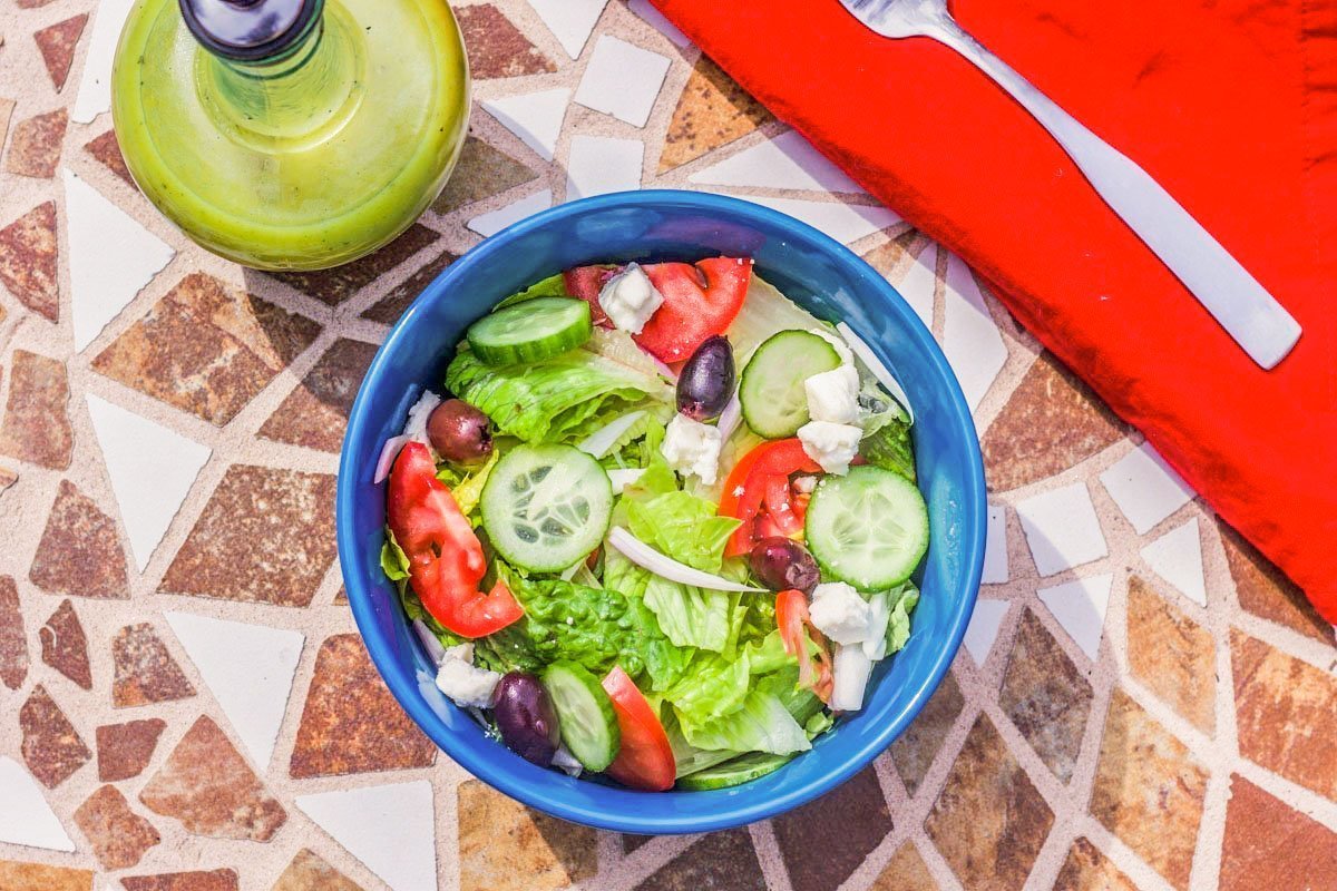 salad in a blue bowl with a red napkin on a marbled table