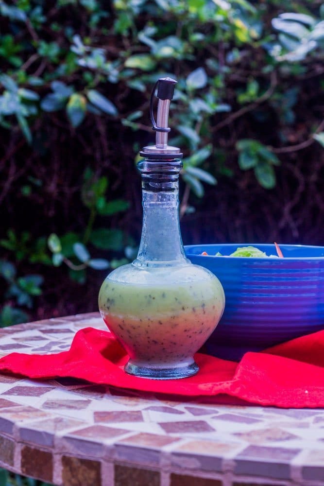 bottle of dressing on red napkin with blue salad bowl