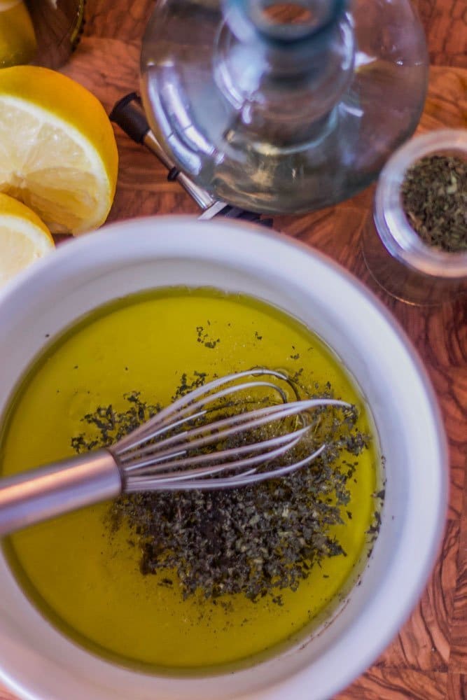 salad dressing in a white bowl with ingredients around it