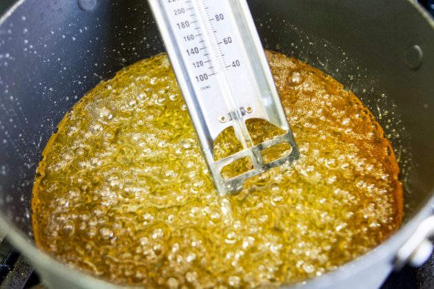 corn syrup boiling in a pot with a candy thermometer in the pot