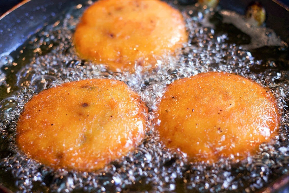 3 potato chops being fried in oil