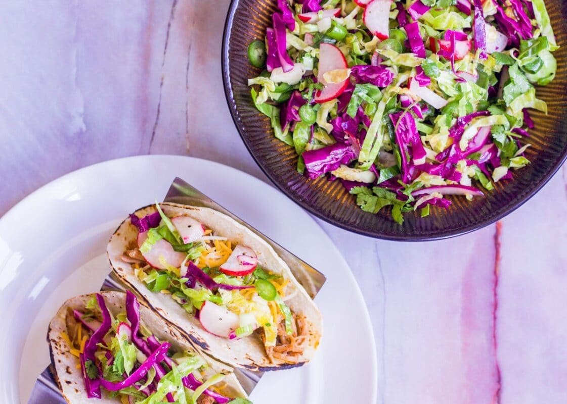 st. patrick's Day recipes coleslaw in a brown bowl with two tacos