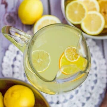 lemonade pitcher with whole and sliced lemons around it