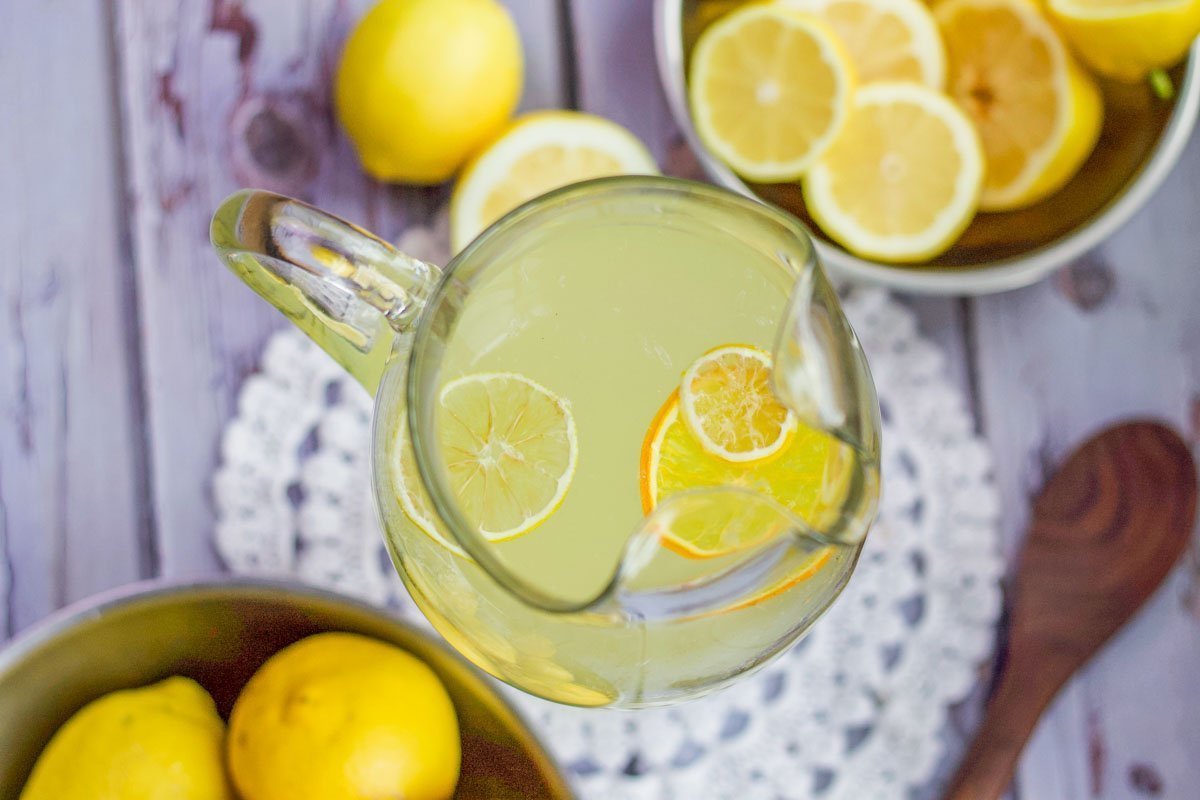 lemonade pitcher with whole and sliced lemons around it