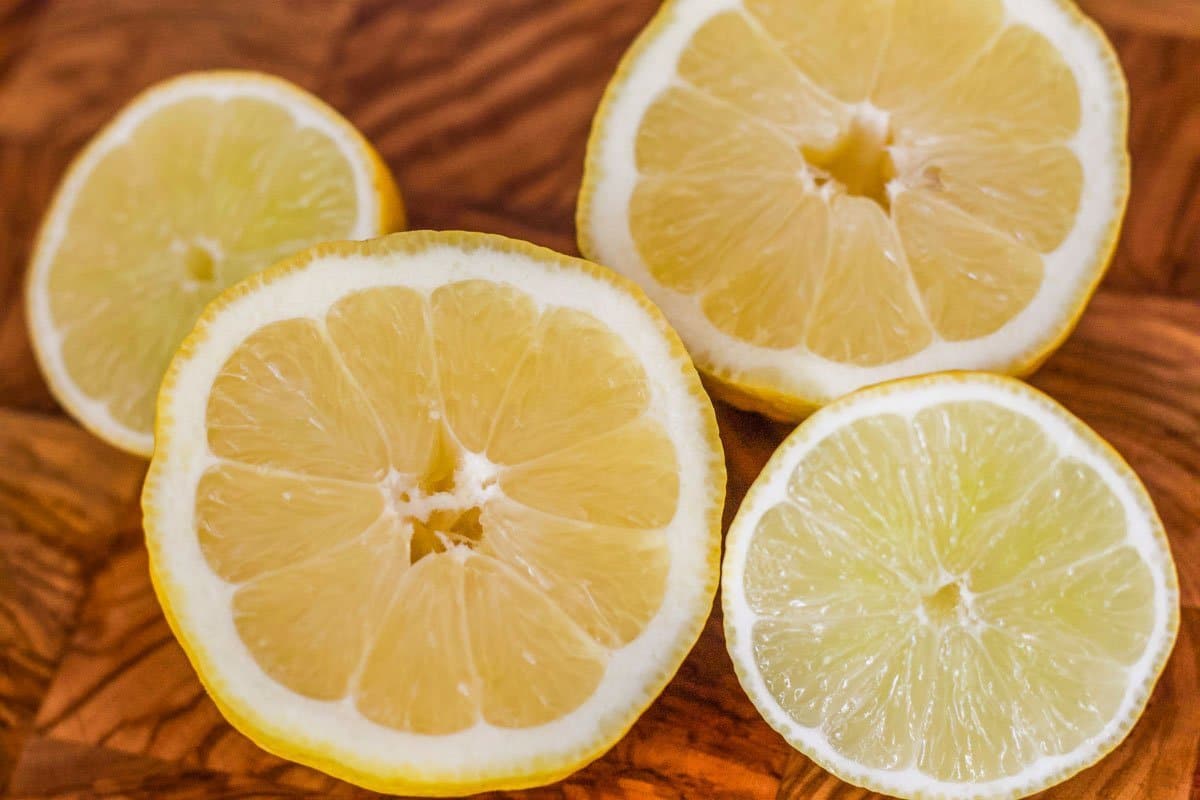 two lemons cut in half on a wooden cutting board