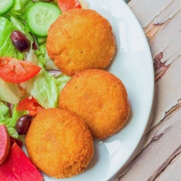 3 potato patties on a white plate with a salad