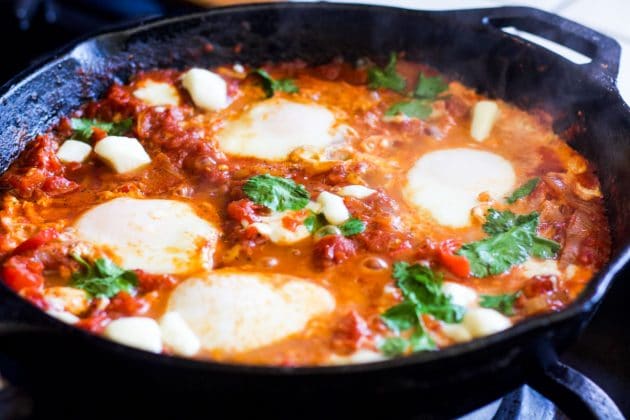 vegetarian shakshuka eggs cooked in tomato sauce in a cast iron pan