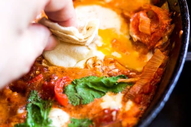 shakshuka with pita bread being dipped into it