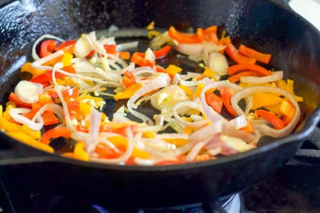 onions and peppers being cooked in a pan