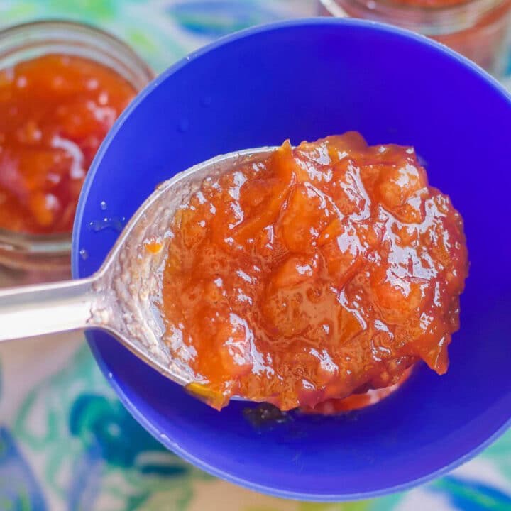 loquat jam in a spoon over a blue funnel