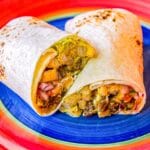 A California burrito sliced in half and placed on a blue and red plate.