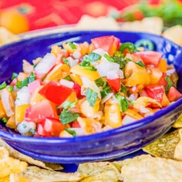 loquat salsa in a blue bowl with chips around it.