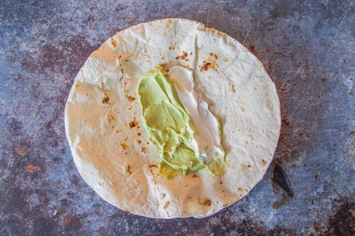 tortilla with guacamole and sour cream in the center, blue background