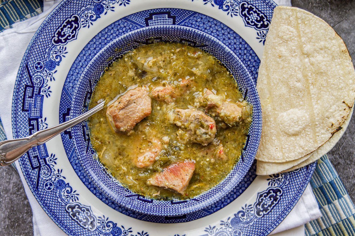 instant pot chili verde in a blue willow bowl with tortillas on the side