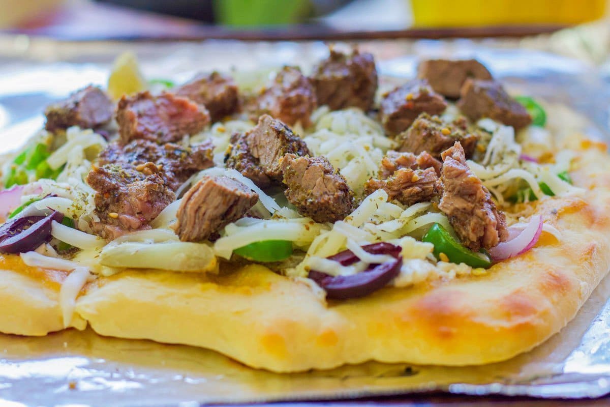  pizza topped with meat and veggies on foil