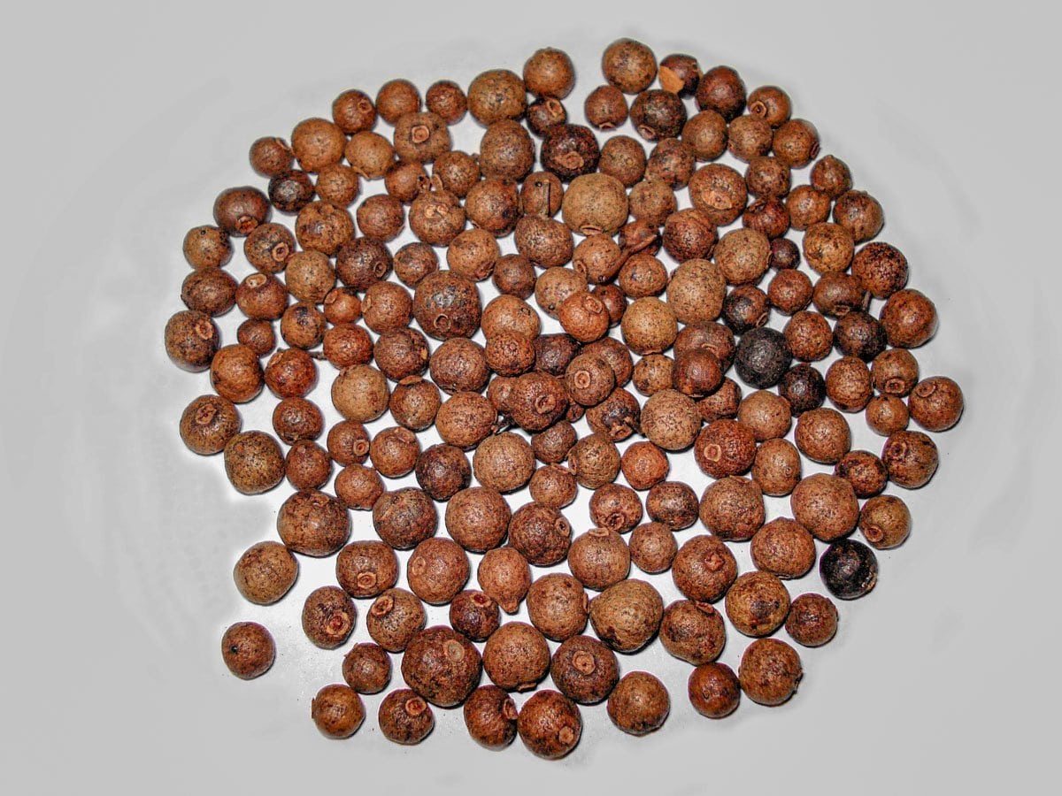 allspice berries on a white surface