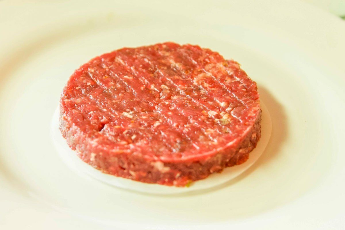 raw bison burger on a white plate