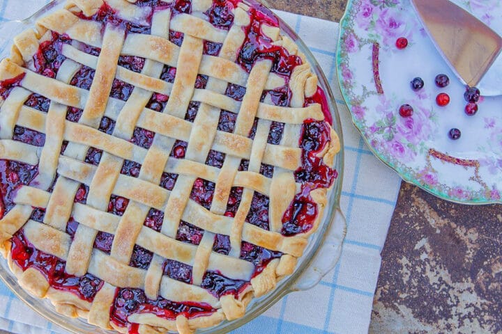 huckleberry pie with lattice top and a plate with huckleberries