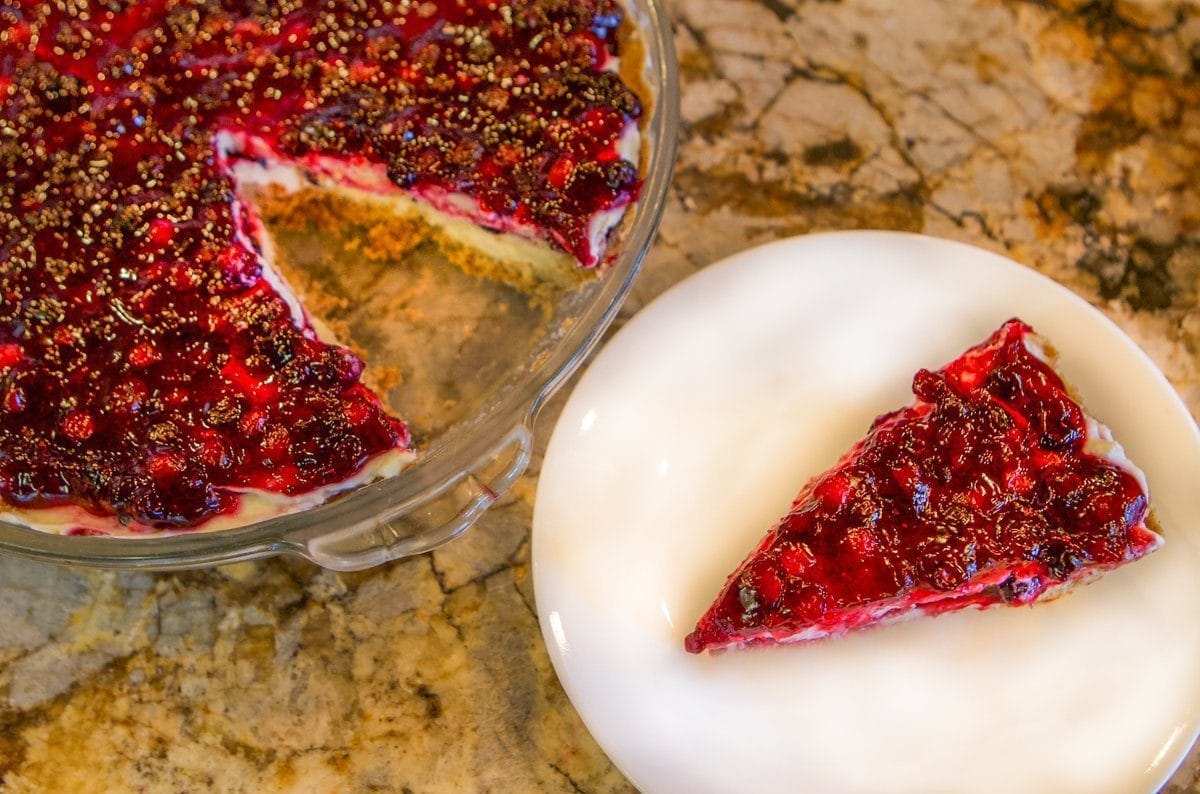 berry cheesecake with a slice removed on a plate next to it