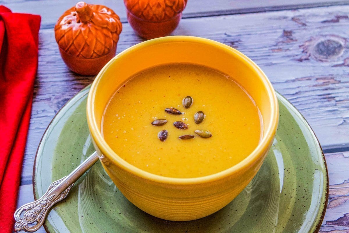 pumpkin soup in a bowl with a red napkin and orange salt and pepper shakers